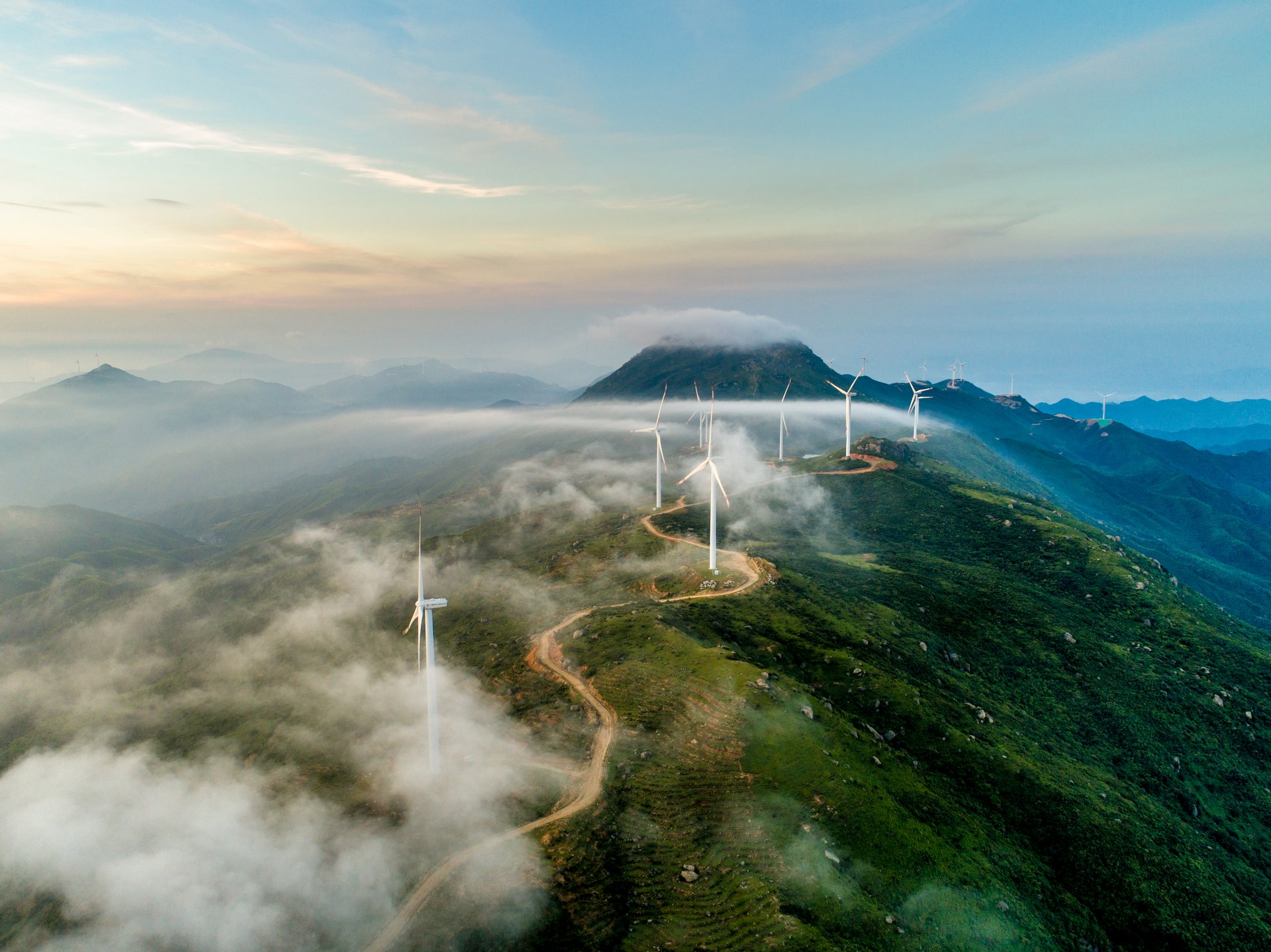 Windräder stehen an einer Straße auf einem hohen Gebirge 