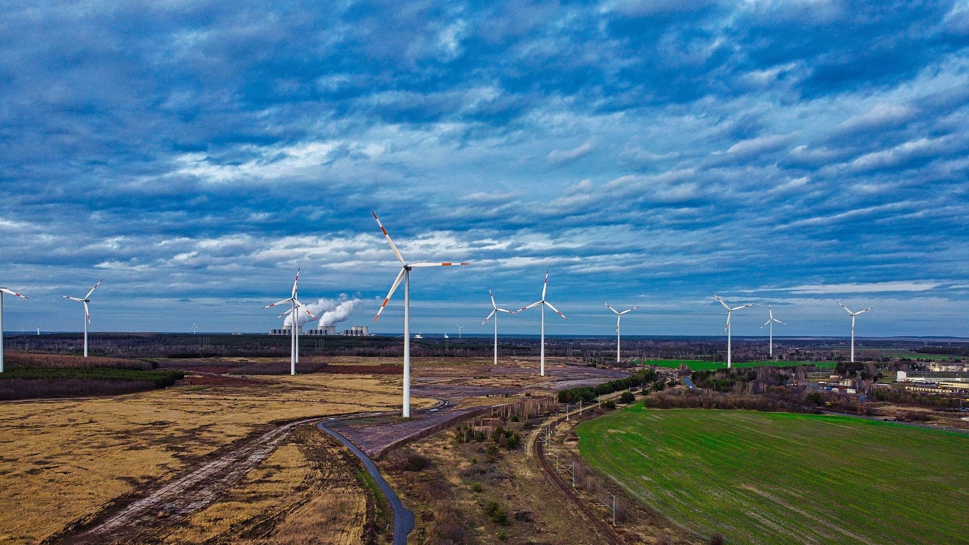 Verteilte Windräder auf Felder unter dunklen Wolken
