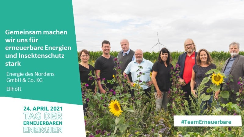 Gruppenfoto der Energie des Nordens GmbH & Co. KG in einem Feld mit Windkraftanlage im Hintergrund