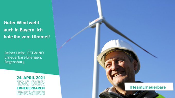 Mann mit Bauhelm vor einer Windkraftanlage