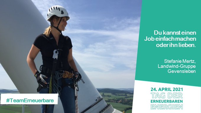 Frau mit Helm und Kletterausrüstung auf einer Windkraftanlage