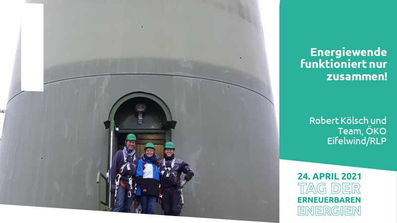 Drei Menschen mit Kletterausrüstung vor einer Windkraftanlage