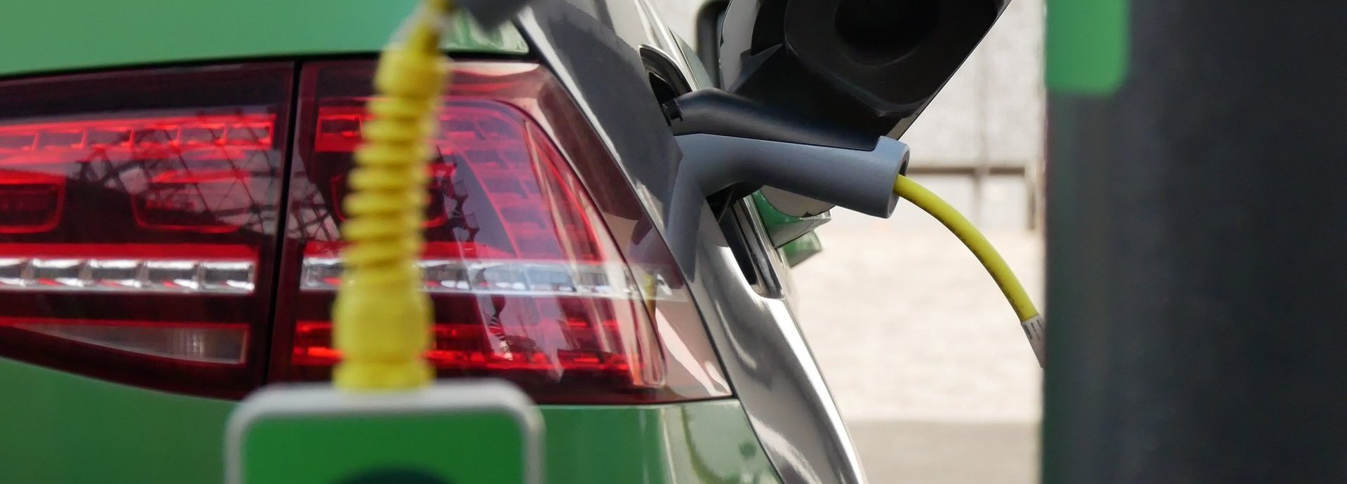Grünes Elektroauto wird an einer elektrischen Ladesäule geladen