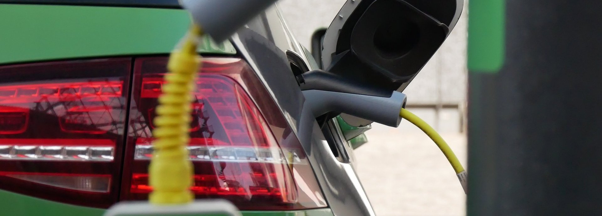 Grünes Elektroauto wird an einer elektrischen Ladesäule geladen