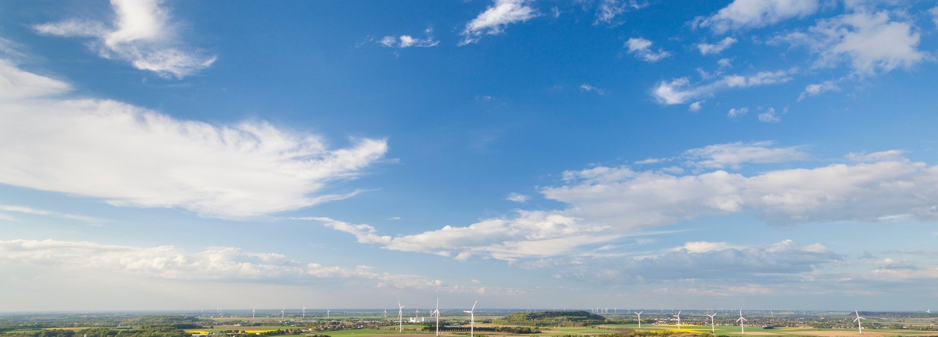 Beschreibung: Landschaft mit Häusern, Windrädern und blauem Himmel