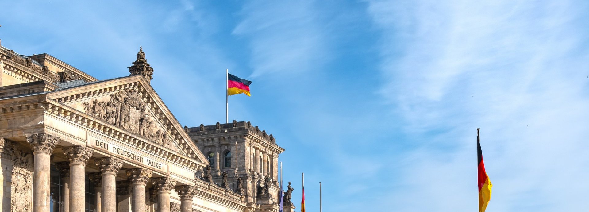 Beschreibung: Bundestagsgebäude mit zwei deutschen Flaggen vor bewölktem blauem Himmel