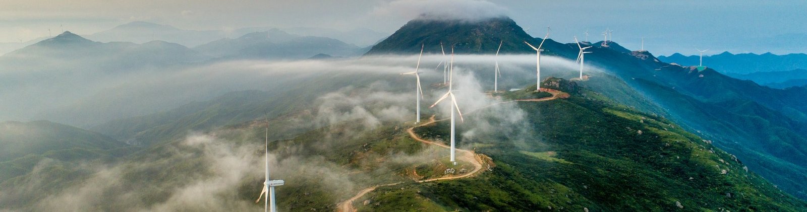 Windräder entlang eines nebeligen Gebirgsweges 