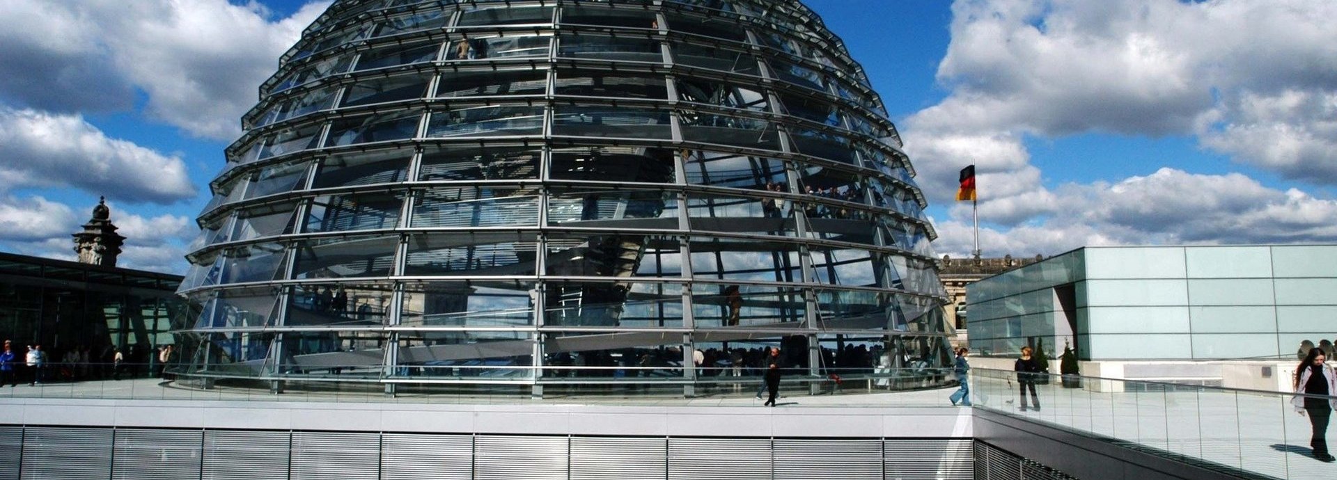 Die Glaskuppel des deutschen Bundestages vor einem leicht bewölkten dunkelblauem Himmel