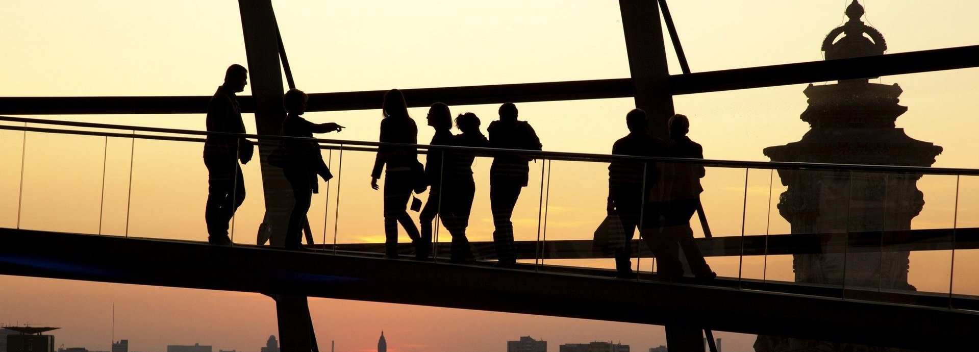 Brücke des Bundestags vor gelbem Himmel mit schattigen Silouhetten von Besuchern