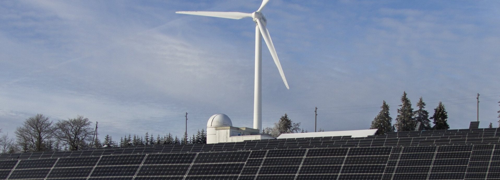 Windrad und Solarkollektoren auf einem schneeweißen Feld