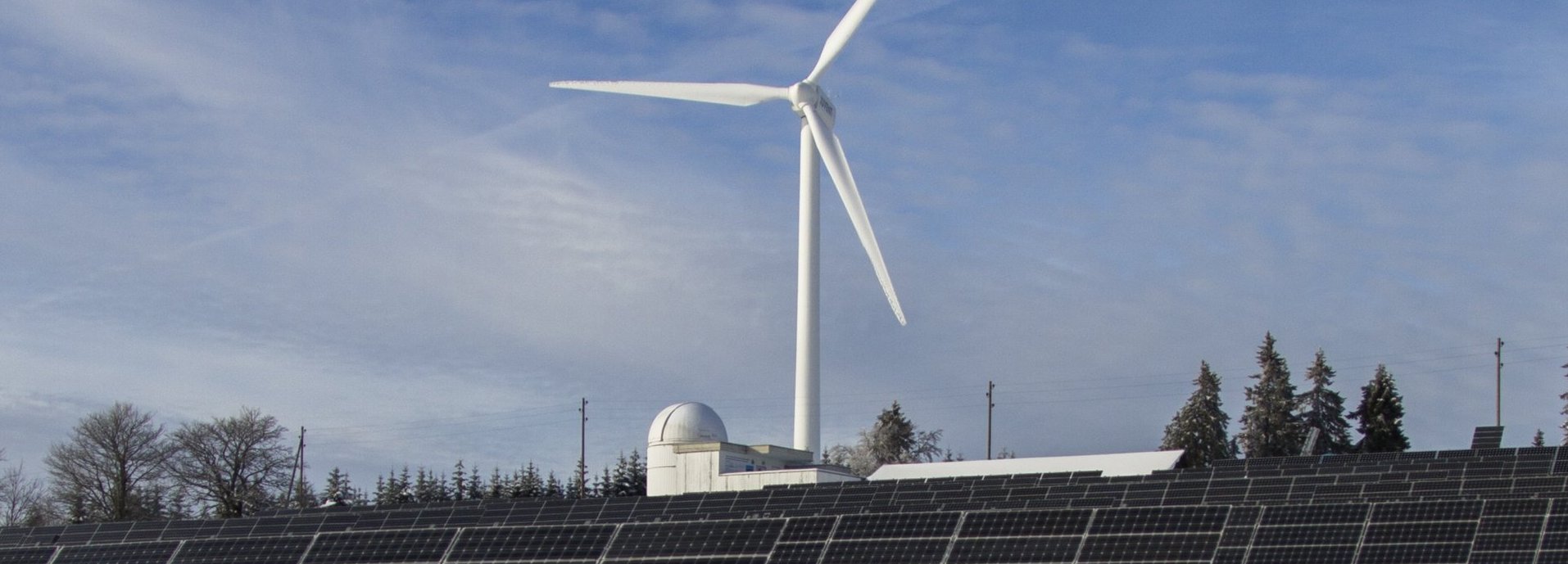 Windrad und Solarkollektoren auf einem schneeweißen Feld
