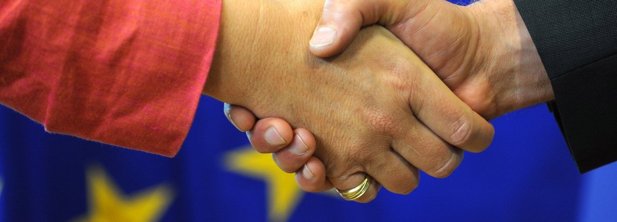 symbolisch für den Händedruck auf einem Hintergrund der europäischen Flagge