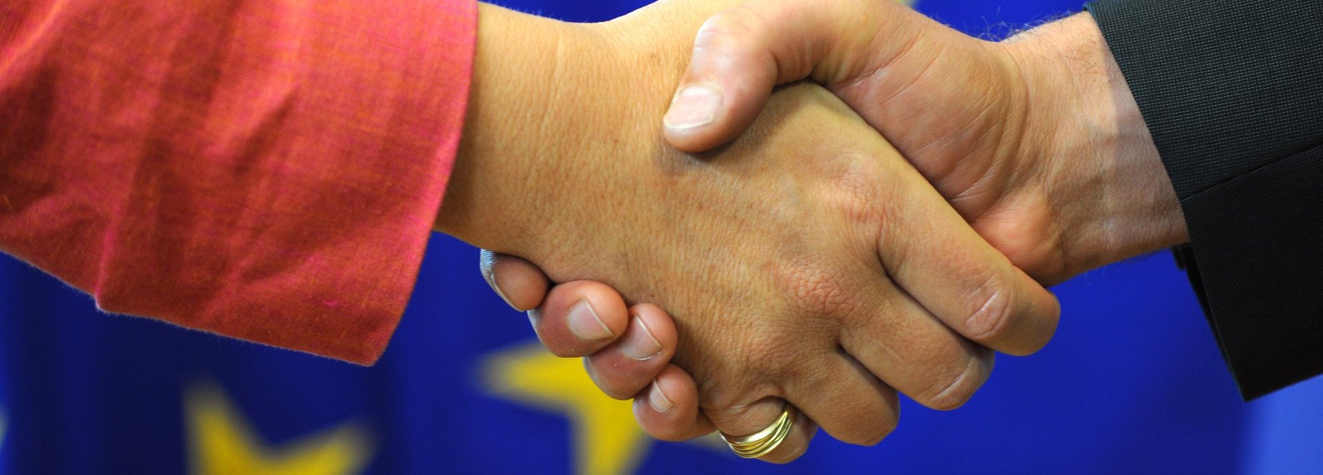 symbolisch für den Händedruck auf einem Hintergrund der europäischen Flagge