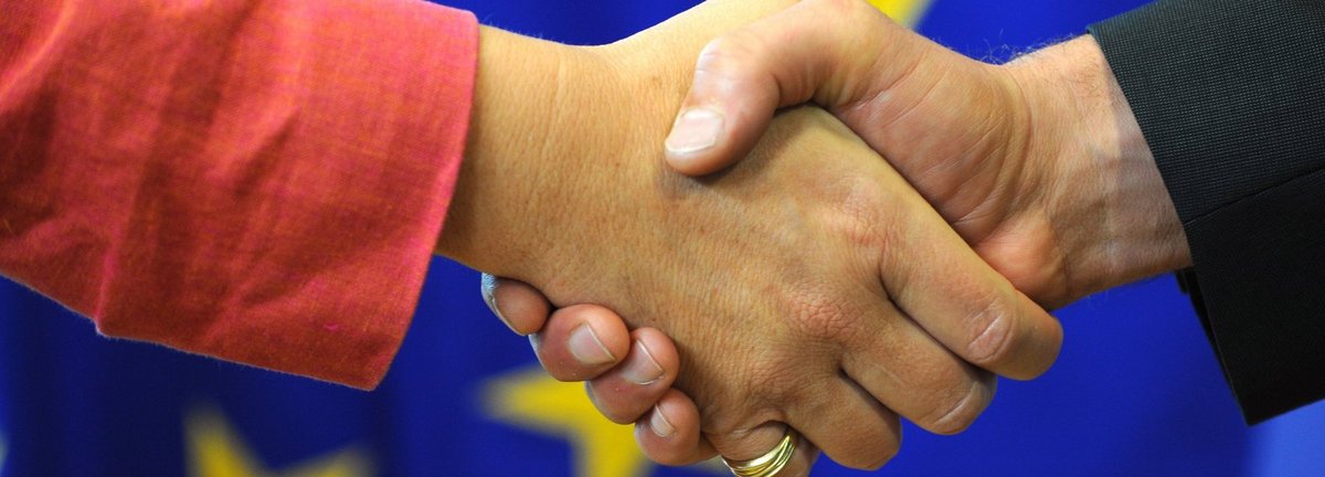 symbolisch für den Händedruck auf einem Hintergrund der europäischen Flagge