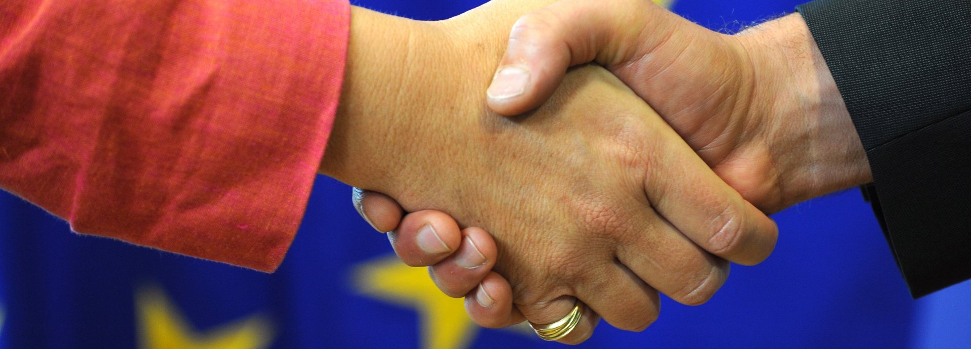 Beschreibung: Händedruck auf einem Hintergrund der europäischen Flagge