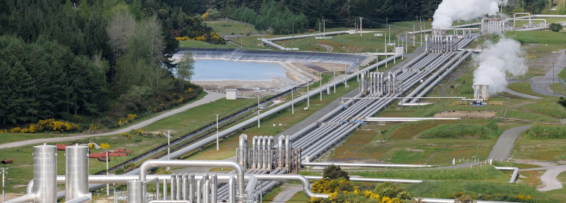 Geothermiekraftwerk auf einem Feld mit Wäldern und Wärmerohren