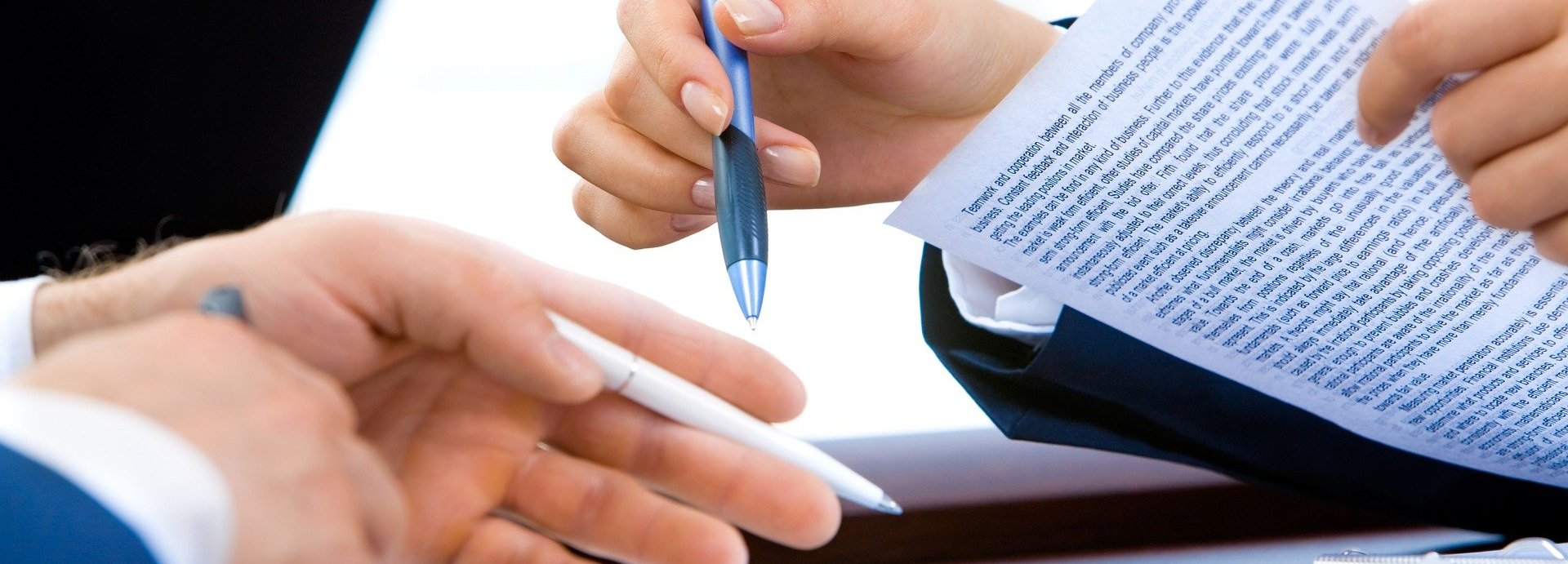 Hände zweier Personen die einen Vertrag unterzeichnen mit Stift und Papier
