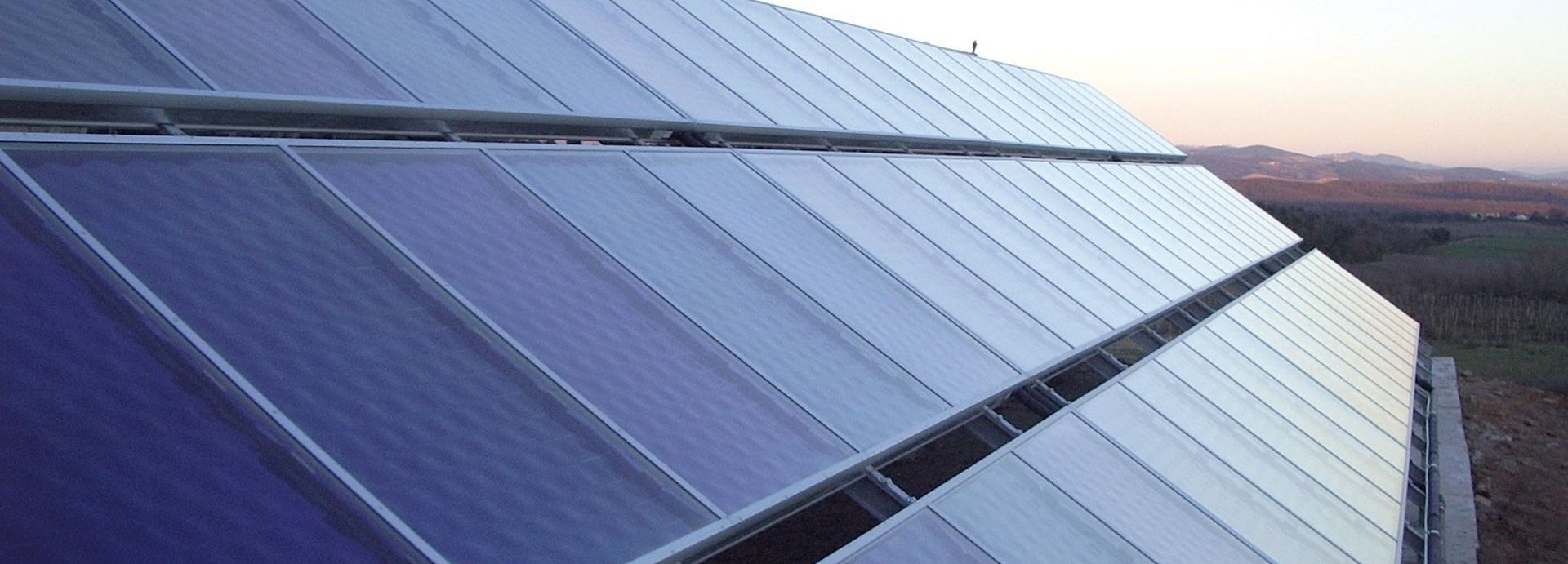 Beschreibung: Nahaufnahme von Solarkollektoren auf einem freien Feld mit hellblauem Himmel