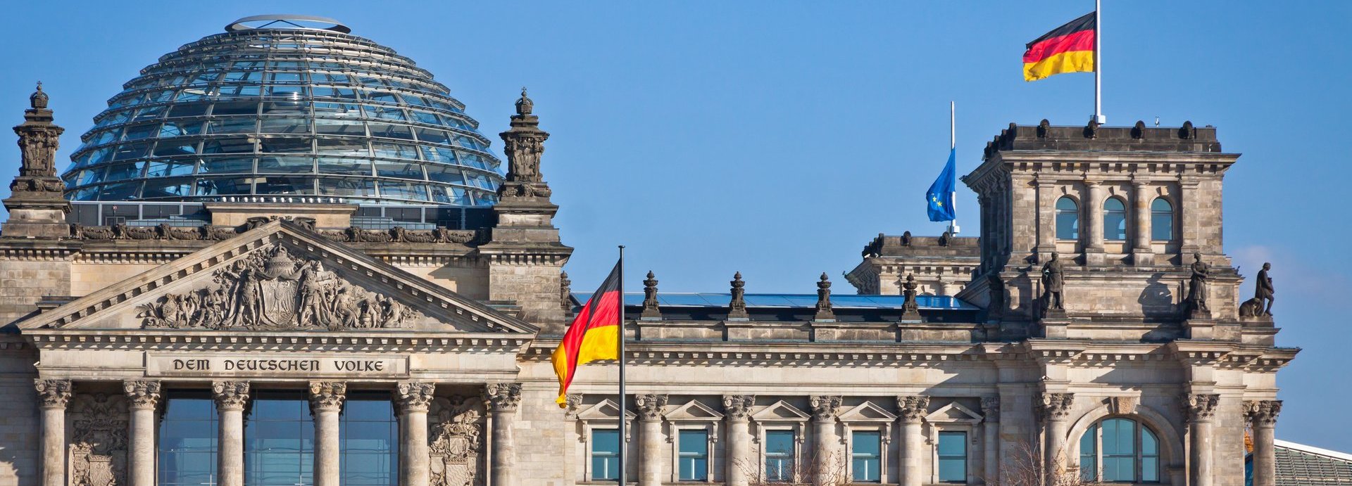 Bundestag mit deutscher Flagge und blauem wolkenlosem Himmel