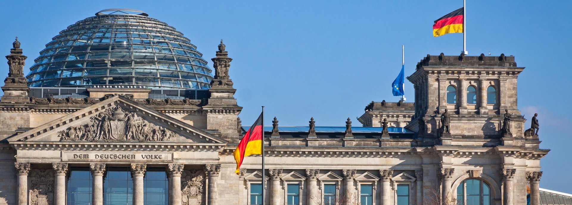 Bundestag mit deutscher Flagge und blauem wolkenlosem Himmel