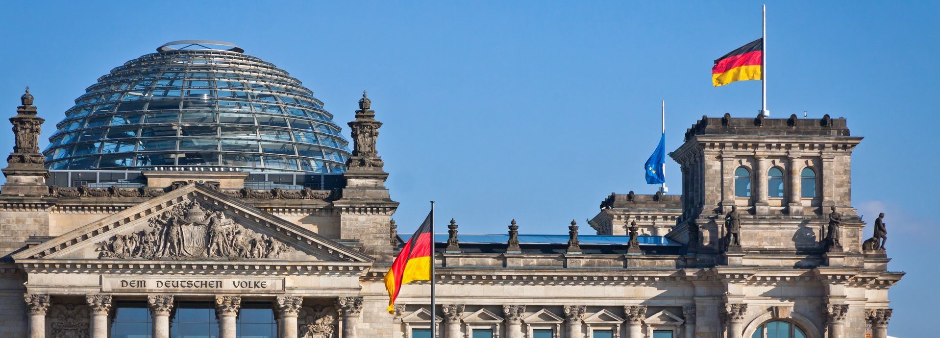 Bundestag mit deutscher Flagge und blauem wolkenlosem Himmel