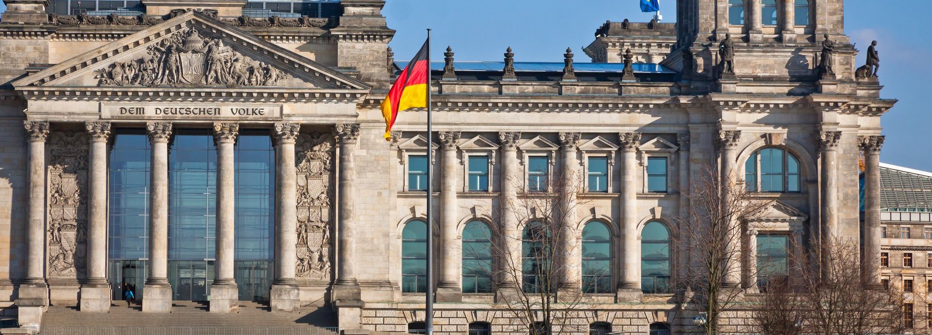 Bundestag mit deutscher Flagge und blauem wolkenlosem Himmel