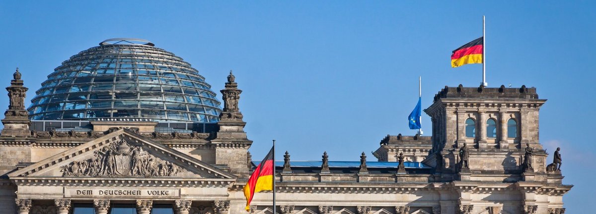 Bundestag mit deutscher Flagge und blauem wolkenlosem Himmel