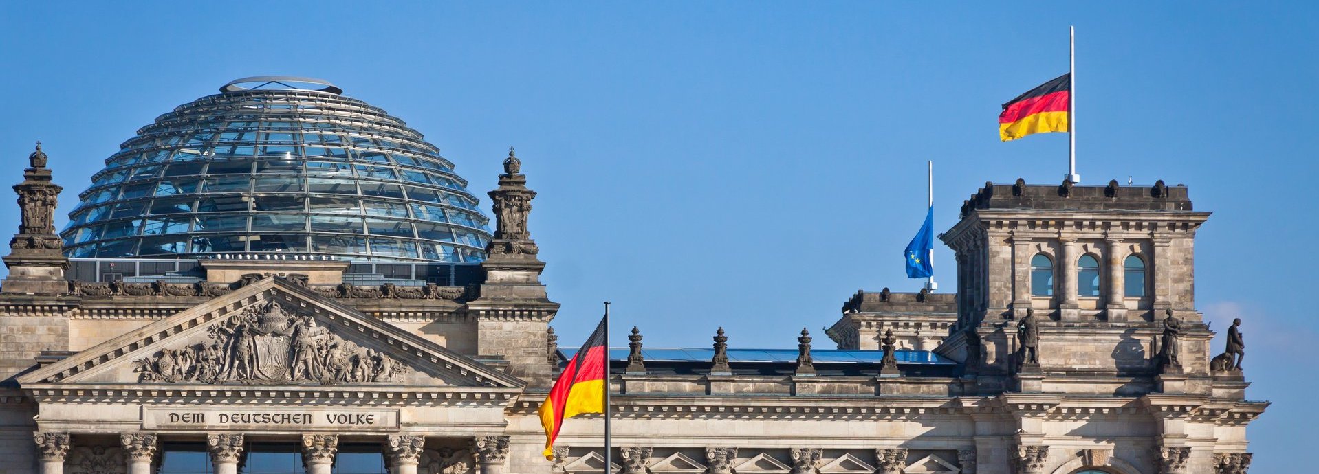 Bundestag mit deutscher Flagge und blauem wolkenlosem Himmel