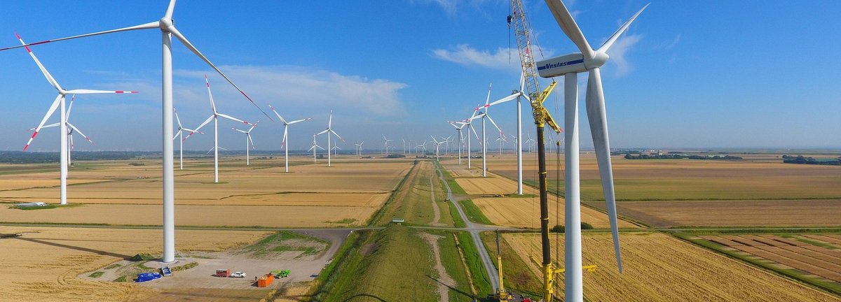 Viele Windräder auf Feldern an denen ein Kran arbeitet