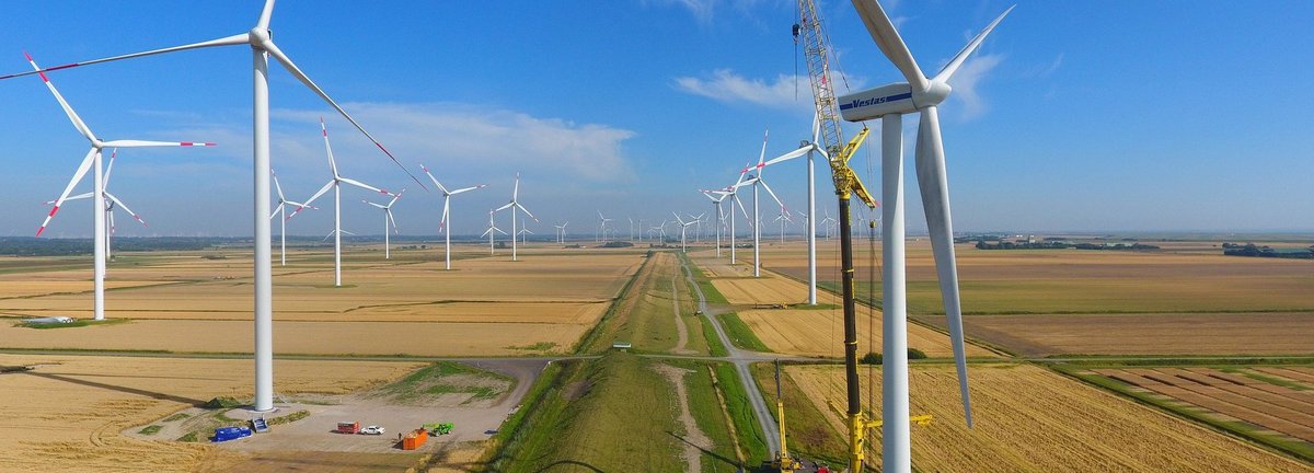 Viele Windräder auf Feldern an denen ein Kran arbeitet