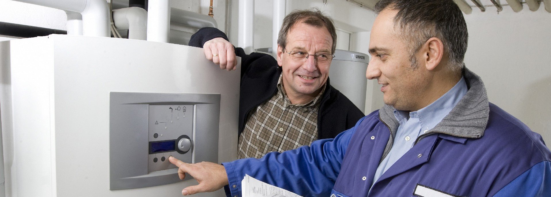 Zwei Männer im Keller an einer weißen Wärmepumpe