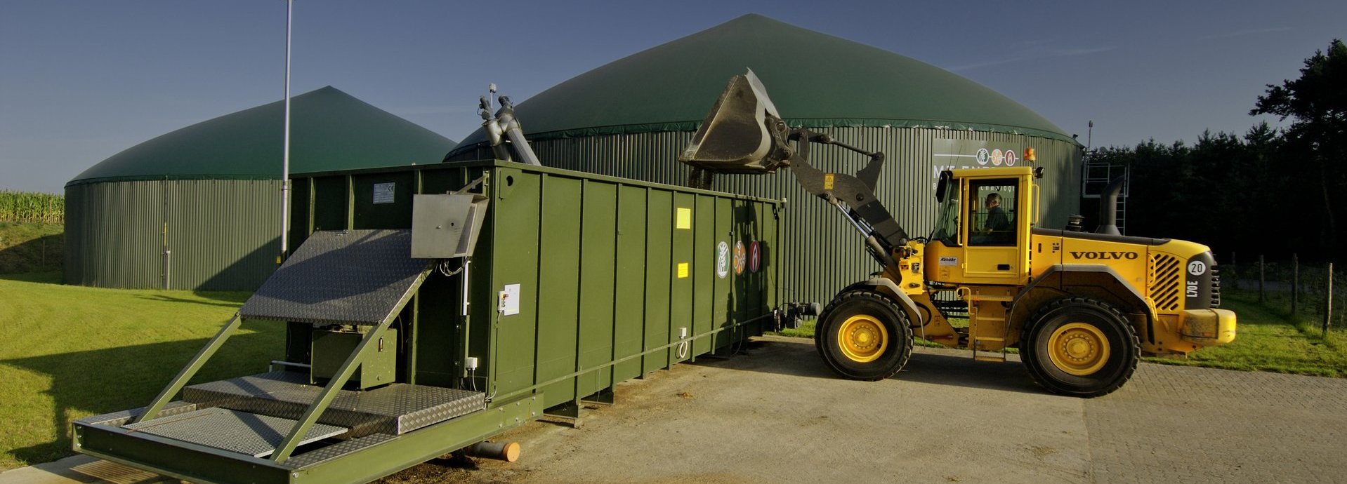 Biogasanlage mit blauem Bagger bei der Arbeit