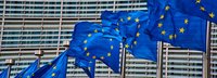 Nahaufnahme des Gebäudes der Europäischen Kommission in Brüssel, davor wehende EU Fahnen