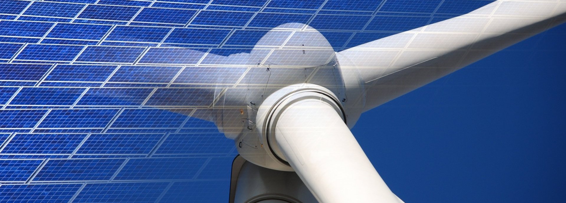 Solarkollektoren eingeblendet vor Nahaufnahme von Windrad mit blauem Hintergrund