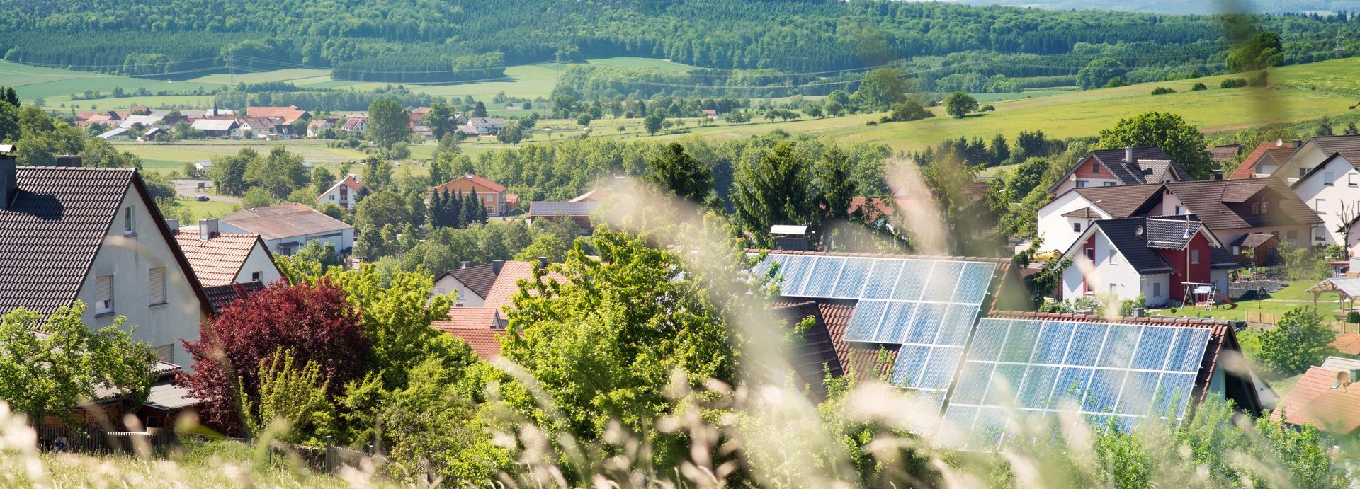 Solarzellen im Hintergrund auf einem Haus in einer Siedlung umgeben von Natur