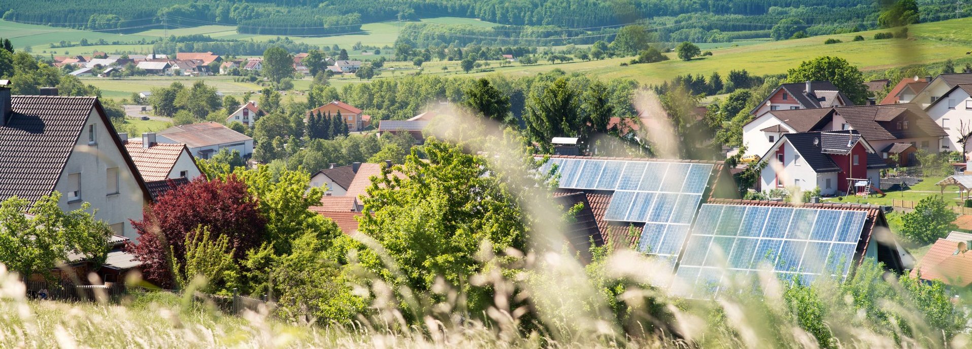 Solarzellen im Hintergrund auf einem Haus in einer Siedlung umgeben von Natur