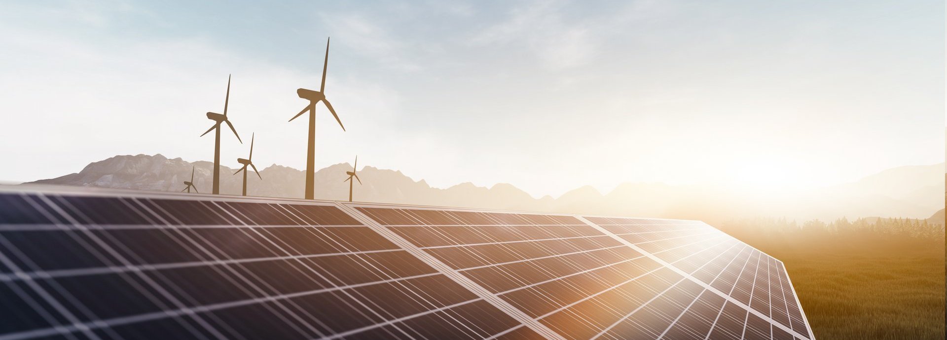 Solarkollektoren und Windräder bei Sonnenaufgang auf einem Feld mit Bergen im Hintergrund