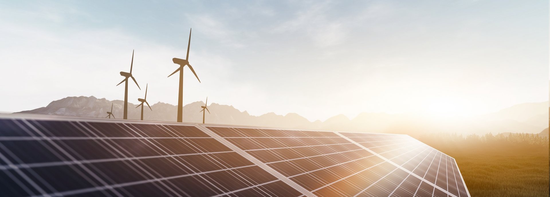 Solarkollektoren und Windräder bei Sonnenaufgang auf einem Feld mit Bergen im Hintergrund