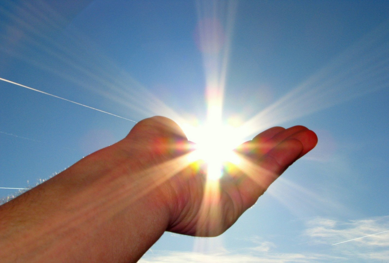Hand hält die scheinende Sonne im Himmel in der Handfläche