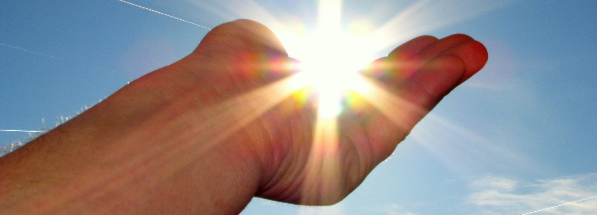 Hand hält die scheinende Sonne im Himmel in der Handfläche