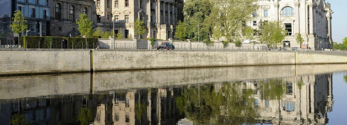 Bildbeschreibung: Außenansicht des deutschen Bundestages und anderer Gebäude fotografiert vom Spreeufer