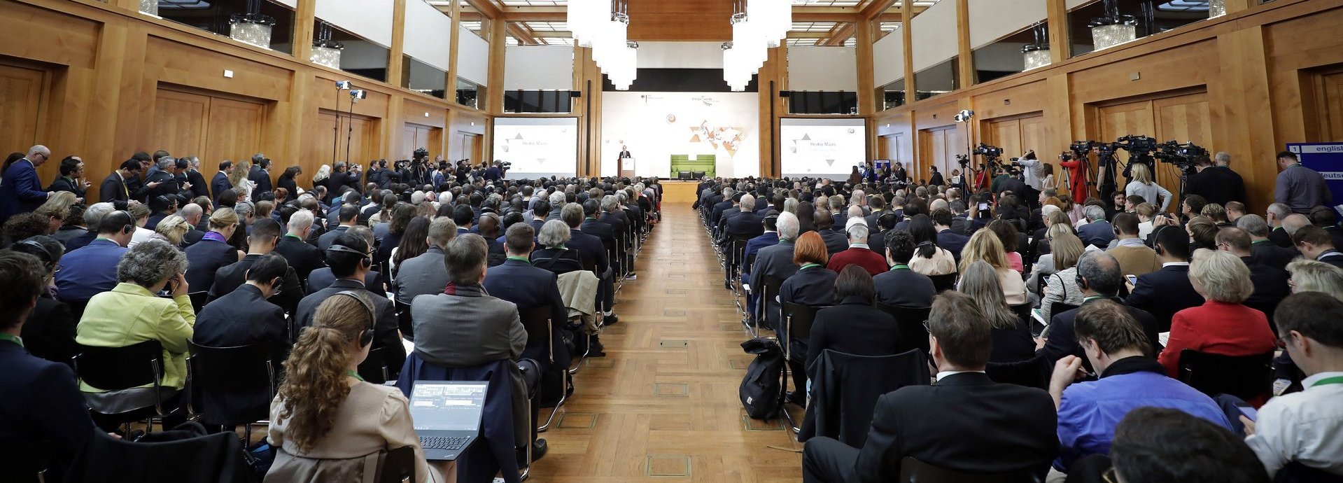 Viele Menschen sitzen in einem großen Saal auf einer BETD Veranstaltung mit Blick auf die Bühne. Die Bühne ist in der Ferne mit einem Redner und dem Green Sofa