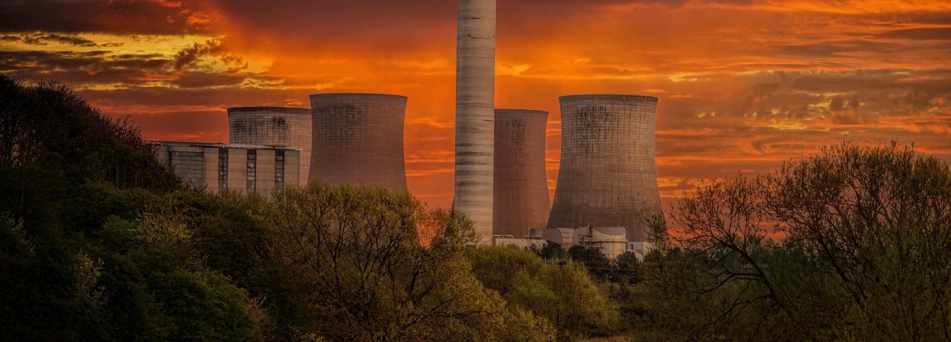 Beschreibung: Weißes Kernkraftwerkssilo unter orangem Himmel bei Sonnenuntergang