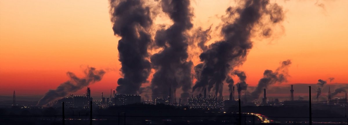 Dunkler Qualm aus Fabrik zieht in Abendhimmel