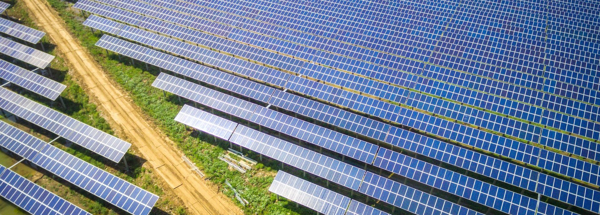 Große Solaranlage mit vielen Kollektoren auf einem Feld getrennt von einem Feldweg
