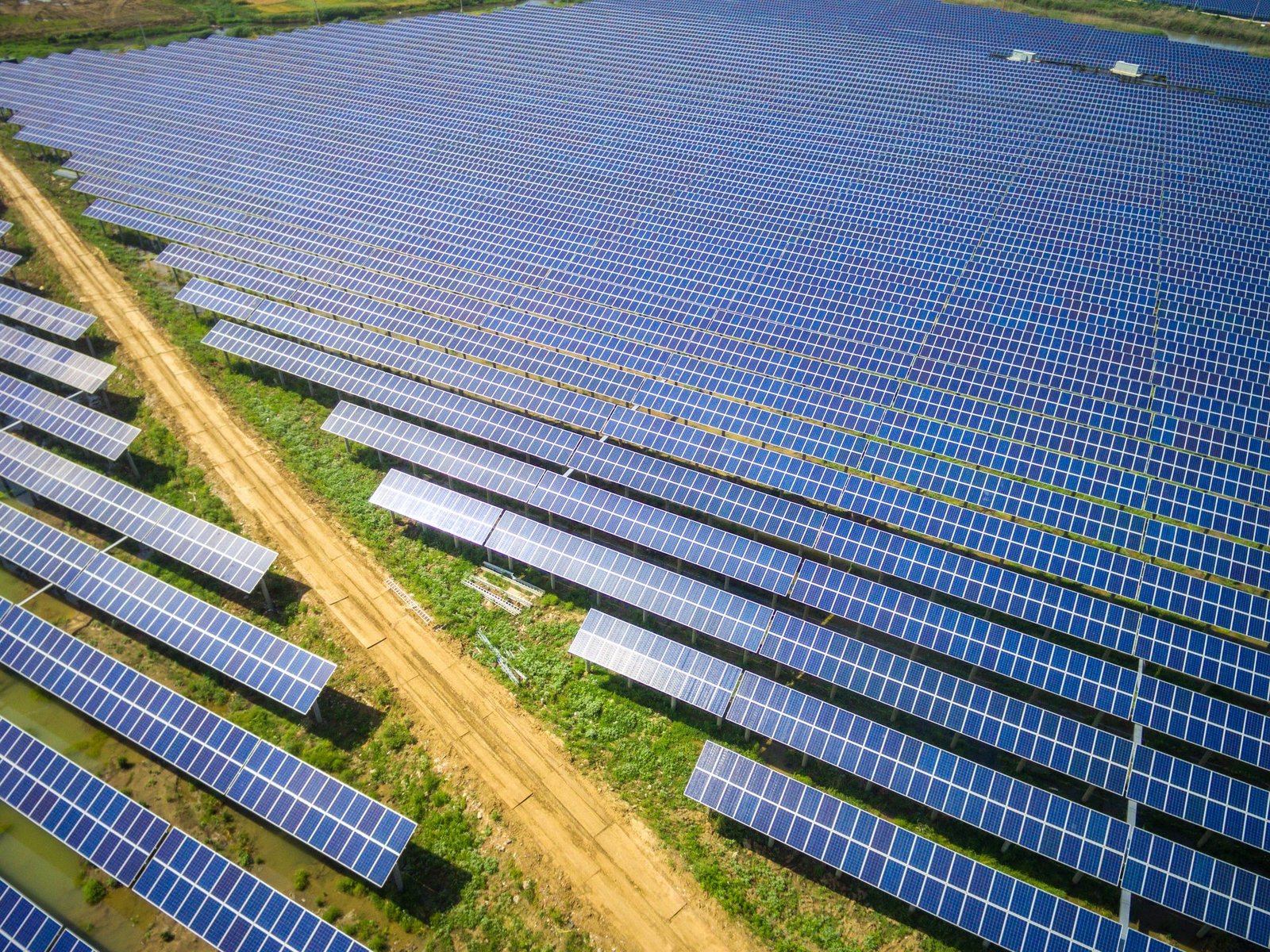 Große Solaranlage mit vielen Kollektoren auf einem Feld getrennt von einem Feldweg