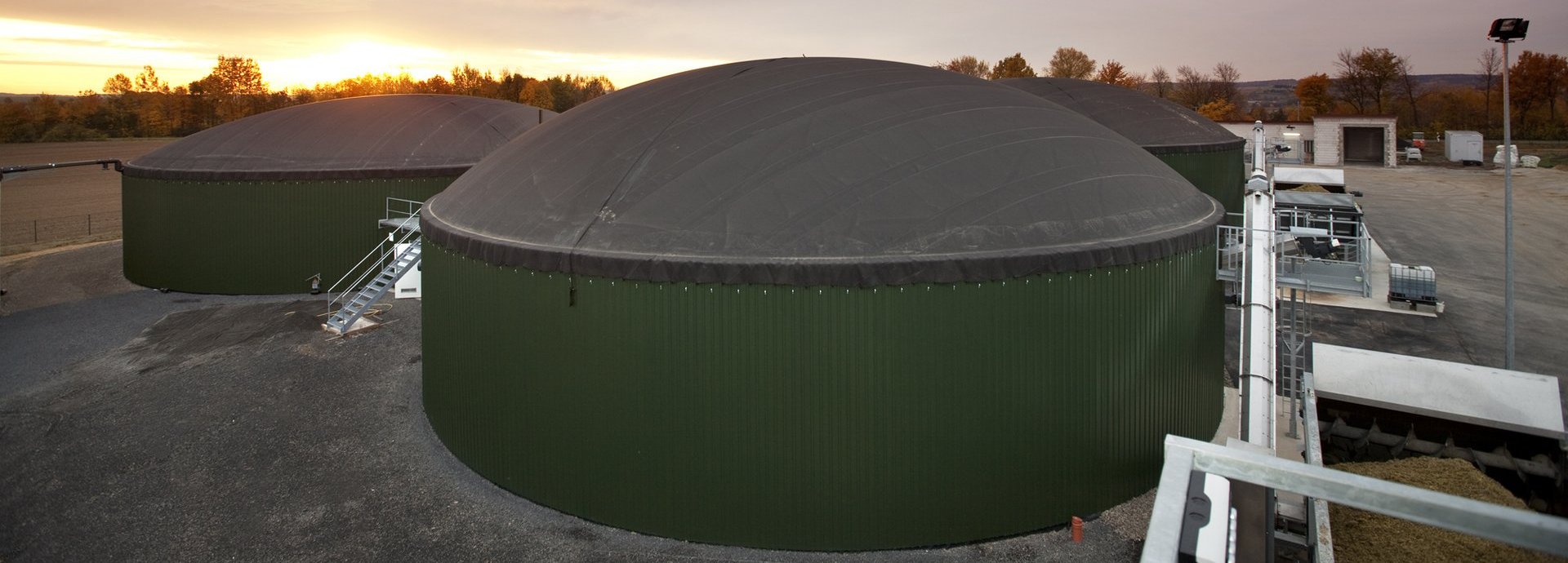 Biogasanlage Wollbrandshausen vor bewölktem Himmel und Sonnenuntergang
