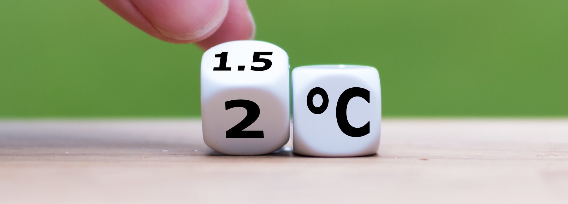 Symbol für die Begrenzung der globalen Erwärmung. Die Hand dreht einen Würfel und ändert den Ausdruck „2°C“ in „1,5°C“ oder umgekehrt.