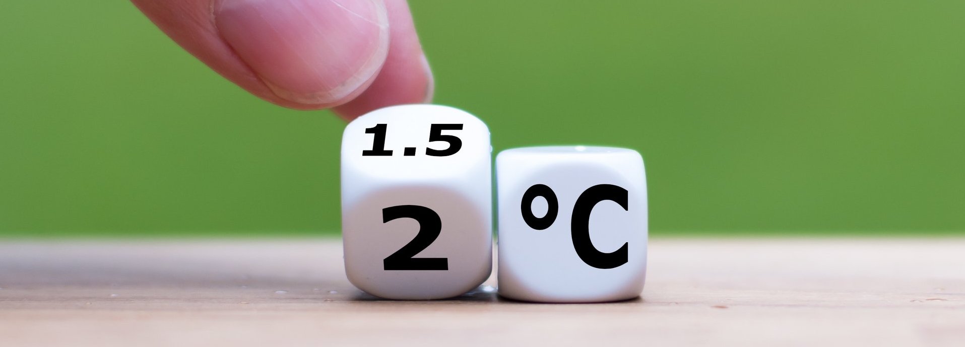 Symbol für die Begrenzung der globalen Erwärmung. Die Hand dreht einen Würfel und ändert den Ausdruck „2°C“ in „1,5°C“ oder umgekehrt.