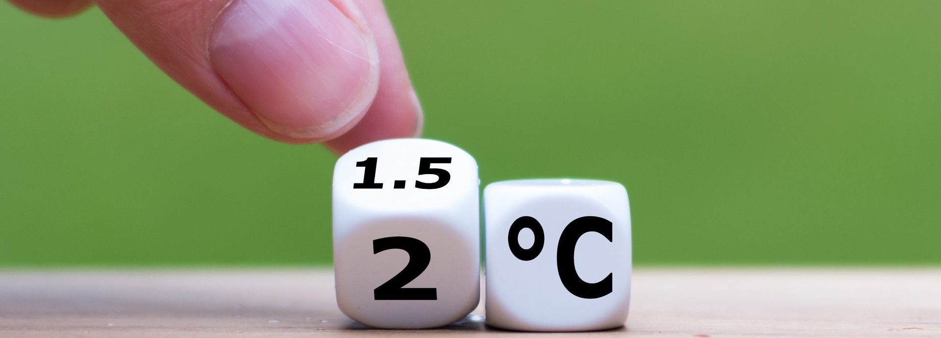 Symbol für die Begrenzung der globalen Erwärmung. Die Hand dreht einen Würfel und ändert den Ausdruck „2°C“ in „1,5°C“ oder umgekehrt.